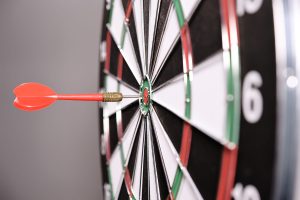a red dart hitting in the center of a dart.
