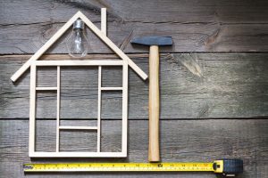 a wooden house with a hammer and a measuring tape.