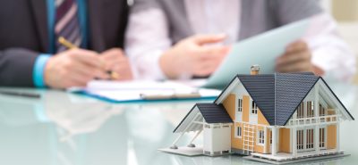 Small house in front of people filling out paperwork